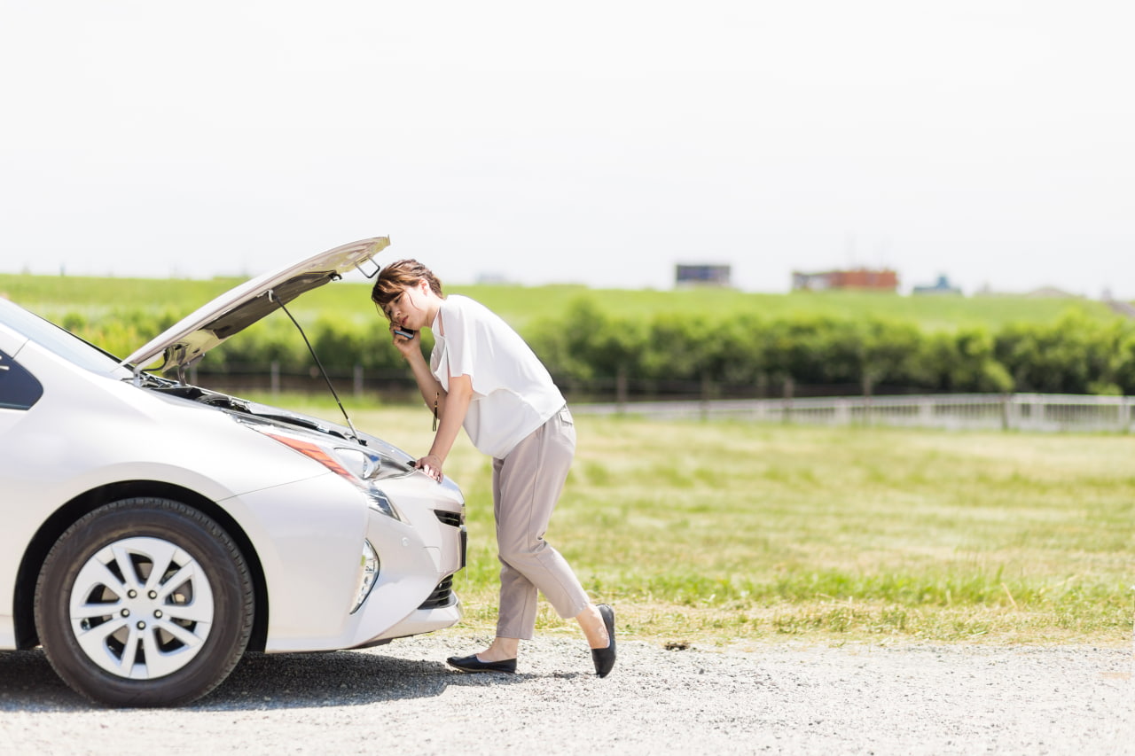 女性の車が故障して困っている様子